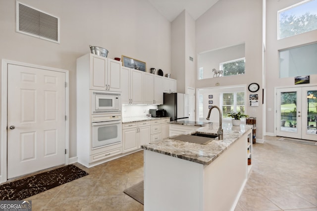 547 E Cardinal Cir, Saint Marys, GA 31558 - kitchen featuring visible vents, high vaulted ceiling, white appliances, and light stone counters