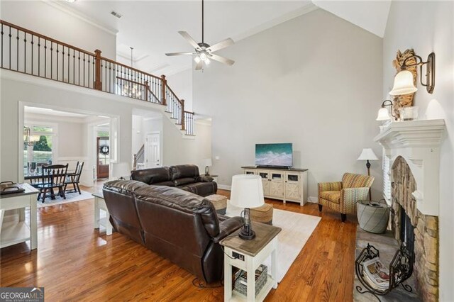 6565 Scottsfield Trce, Cumming, GA 30028 - living area with a fireplace with raised hearth, wood finished floors, stairs, high vaulted ceiling, and ceiling fan