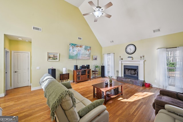 living room with light wood finished floors, visible vents, a ceiling fan, and high vaulted ceiling