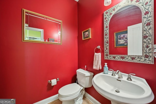 bathroom with toilet, a sink, and baseboards