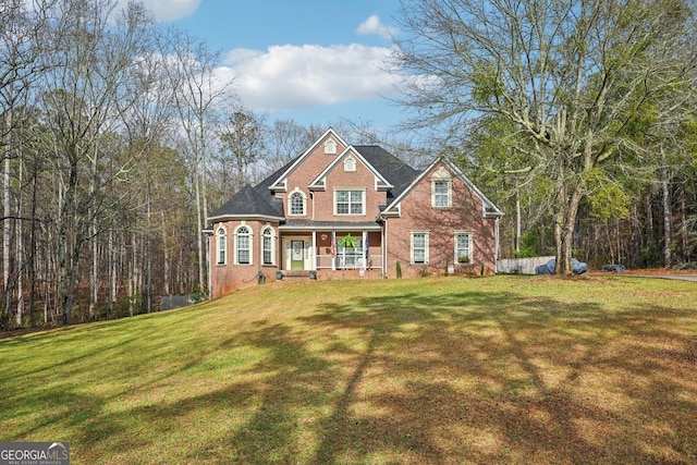 view of front facade with brick siding, a front yard, and covered porch