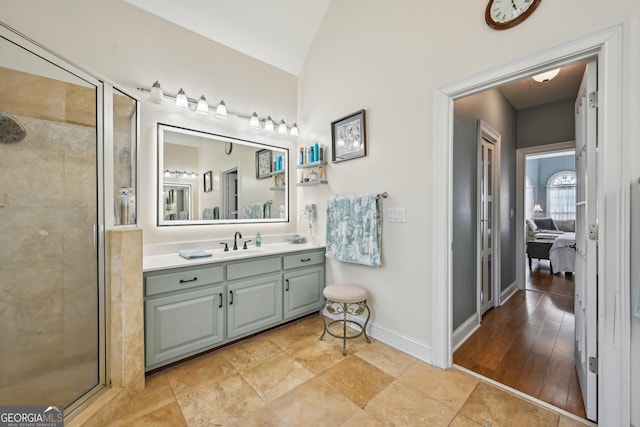 bathroom with a shower stall, baseboards, vanity, and vaulted ceiling