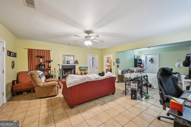 living area featuring a ceiling fan, light tile patterned flooring, visible vents, and a fireplace