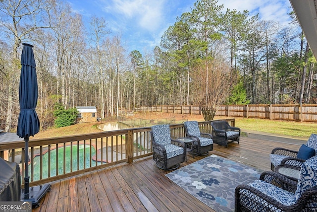 wooden terrace featuring an outdoor structure, a yard, a fenced backyard, and a storage unit