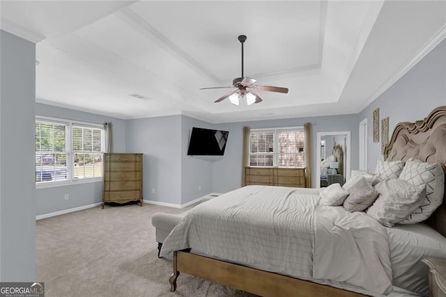 bedroom featuring a raised ceiling, a ceiling fan, ornamental molding, baseboards, and light colored carpet