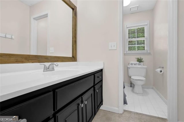bathroom with vanity, toilet, tile patterned flooring, and baseboards
