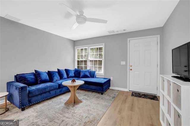 living area with visible vents, baseboards, a ceiling fan, and wood finished floors