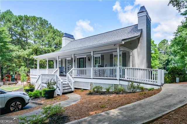 country-style home featuring a chimney, a porch, and a shingled roof