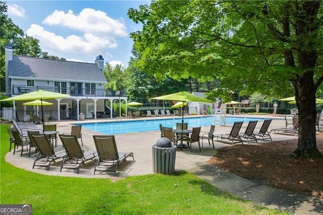 pool featuring fence, a lawn, and a patio