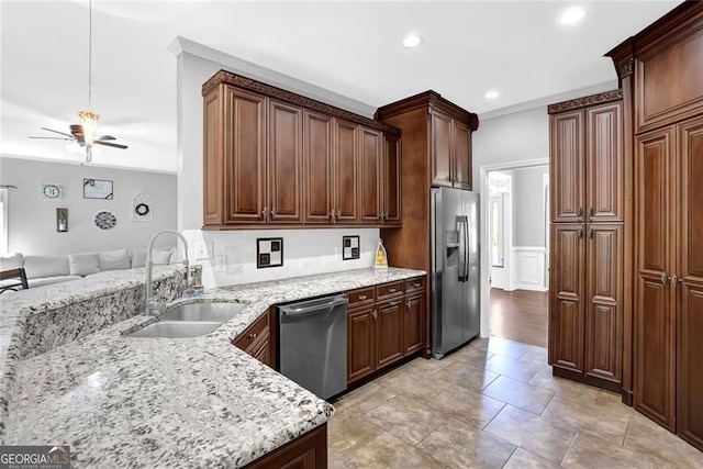 kitchen featuring light stone counters, a sink, appliances with stainless steel finishes, open floor plan, and ceiling fan