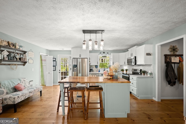 366 Crabapple Rdg, Clarkesville, GA 30523 - kitchen featuring stainless steel appliances, light wood-type flooring, white cabinetry, wood counters, and a breakfast bar area