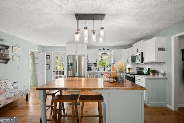 366 Crabapple Rdg, Clarkesville, GA 30523 - kitchen featuring a textured ceiling, light wood-style floors, appliances with stainless steel finishes, and tasteful backsplash