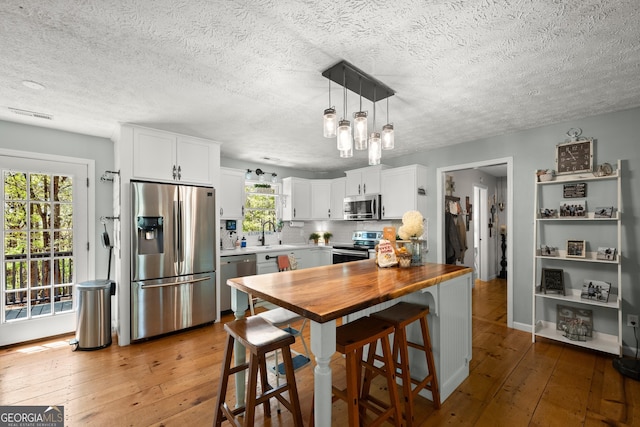 366 Crabapple Rdg, Clarkesville, GA 30523 - kitchen featuring white cabinets, a sink, light wood-style floors, decorative backsplash, and appliances with stainless steel finishes