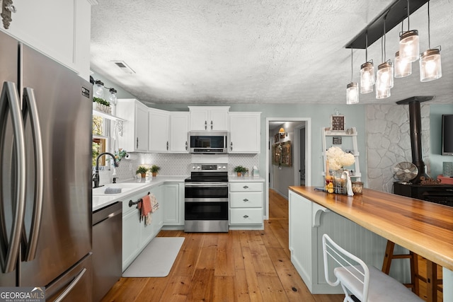 366 Crabapple Rdg, Clarkesville, GA 30523 - kitchen with stainless steel appliances, light wood-style flooring, a sink, visible vents, and a wood stove