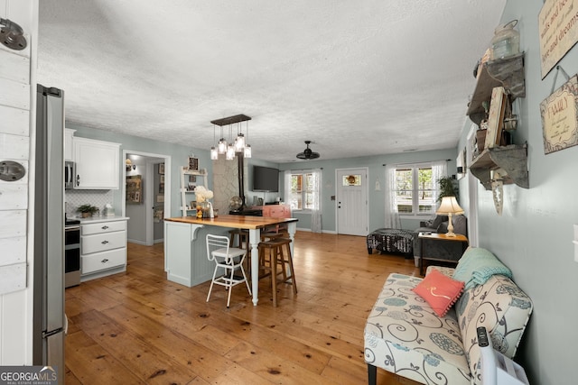 366 Crabapple Rdg, Clarkesville, GA 30523 - kitchen featuring white cabinets, a textured ceiling, open floor plan, a kitchen bar, and butcher block countertops