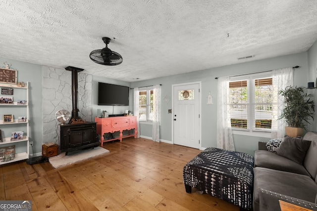 366 Crabapple Rdg, Clarkesville, GA 30523 - living room featuring a ceiling fan, a textured ceiling, hardwood / wood-style flooring, a wood stove, and visible vents