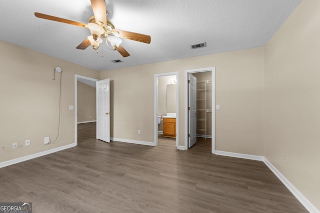 203 Old Pond Dr W, Kingsland, GA 31548 - unfurnished bedroom with dark wood-type flooring, baseboards, a textured ceiling, ceiling fan, and ensuite bathroom