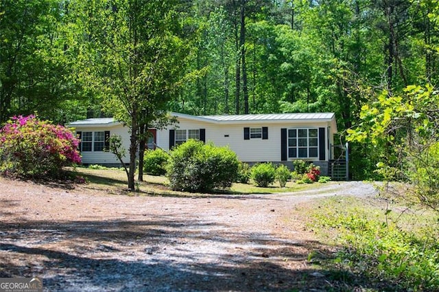 1530 Mcbrayer, Temple, GA 30179 - view of front facade featuring metal roof, driveway, and a forest view