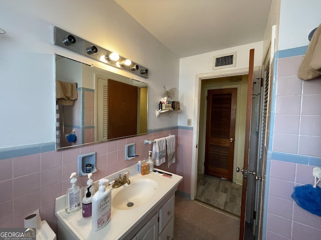 1105 College St, Bainbridge, GA 39819 - bathroom with visible vents, wainscoting, vanity, and tile walls