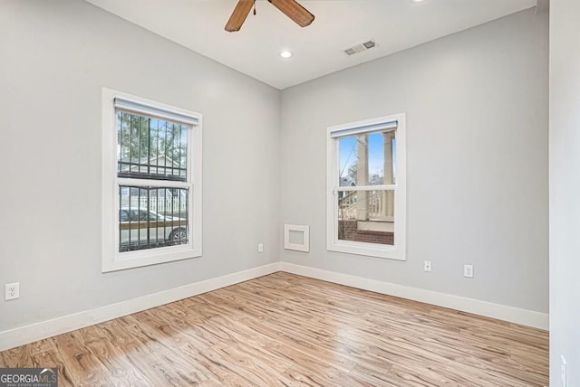 unfurnished room featuring baseboards, wood finished floors, visible vents, and a ceiling fan