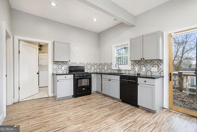 kitchen with dark countertops, gray cabinetry, a sink, and black appliances