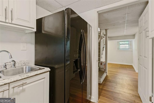 3501 Wesley Chapel Rd, Decatur, GA 30034 - kitchen featuring black refrigerator with ice dispenser, a sink, light wood finished floors, white cabinets, and a paneled ceiling