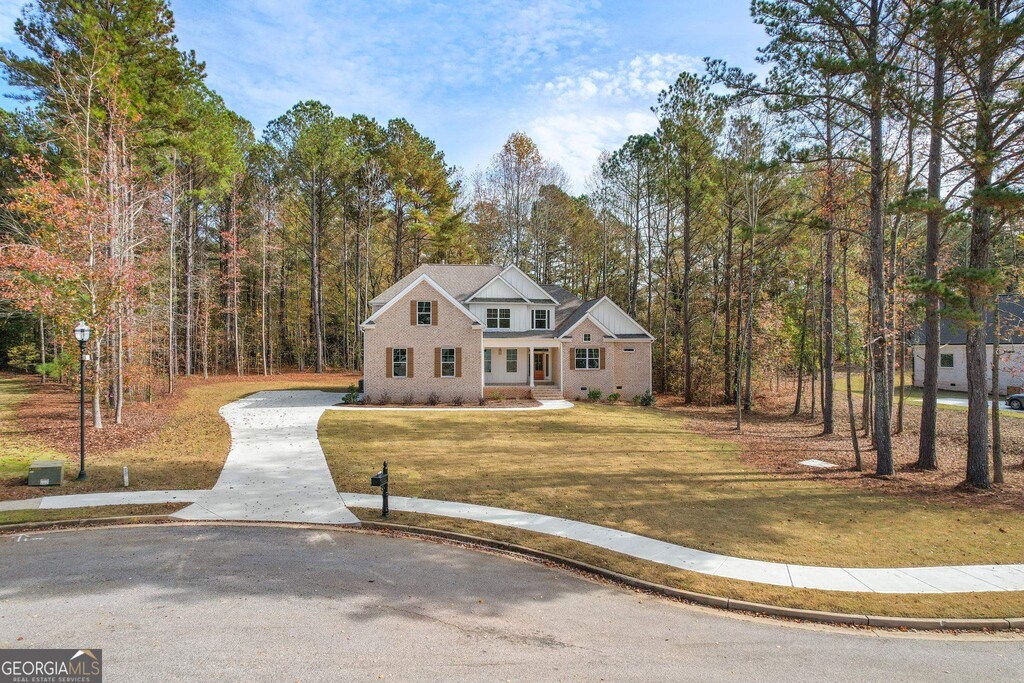 2002 Millstream Ct, Griffin, GA 30224 - traditional home with a front yard, a wooded view, and concrete driveway