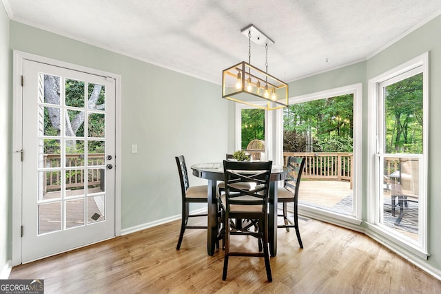 dining space with crown molding, baseboards, a textured ceiling, light wood-style flooring, and a notable chandelier