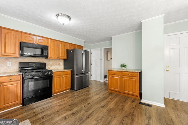 kitchen featuring dark wood-style flooring, brown cabinetry, decorative backsplash, visible vents, and black appliances