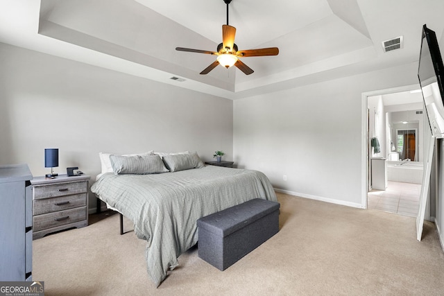 bedroom with visible vents, a raised ceiling, and light colored carpet