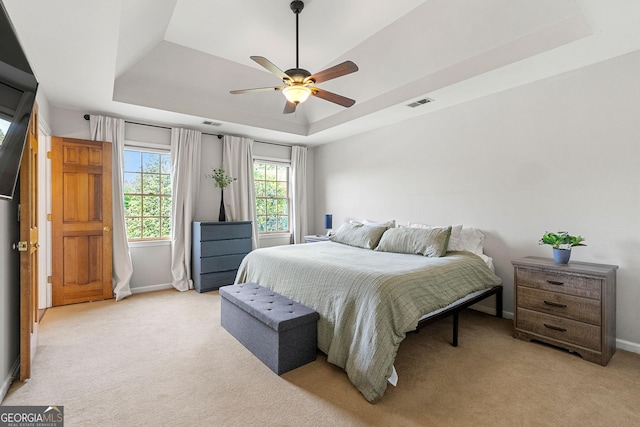 bedroom featuring a raised ceiling, baseboards, light carpet, and visible vents