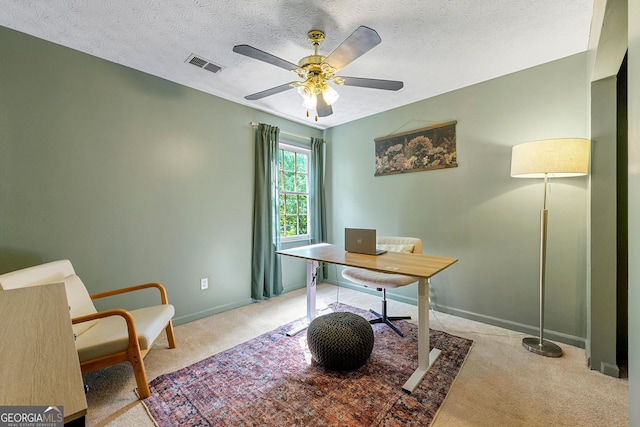 carpeted office space featuring a ceiling fan, baseboards, visible vents, and a textured ceiling
