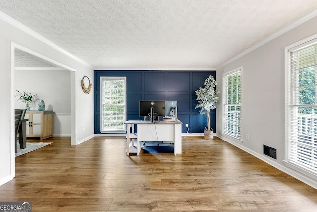home office featuring a textured ceiling, baseboards, ornamental molding, and wood finished floors