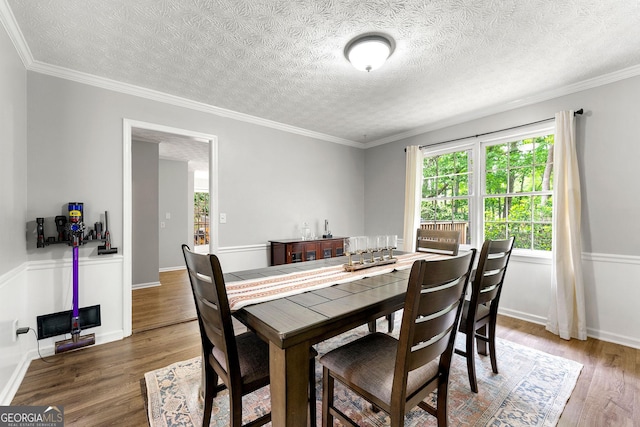 dining area with crown molding, a textured ceiling, and wood finished floors