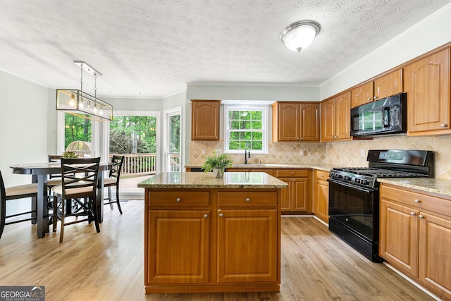 kitchen featuring a center island, light stone countertops, black appliances, and light wood-type flooring