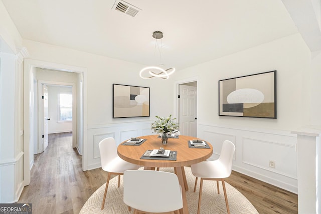1258 Lyle Ave, East Point, GA 30344 - dining space with visible vents, wainscoting, a decorative wall, light wood finished floors, and a notable chandelier