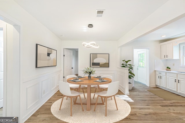 1258 Lyle Ave, East Point, GA 30344 - dining room featuring light wood-style floors, wainscoting, a decorative wall, and visible vents