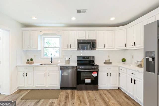 1258 Lyle Ave, East Point, GA 30344 - kitchen featuring visible vents, white cabinets, a sink, light wood finished floors, and appliances with stainless steel finishes