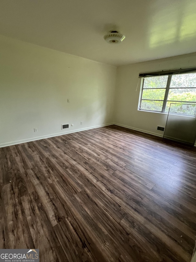 spare room featuring dark wood-style flooring, baseboards, and visible vents