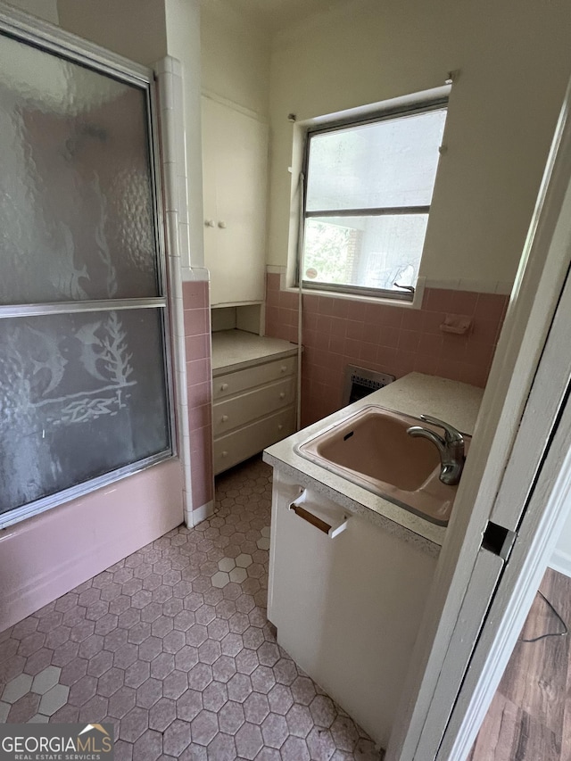 laundry area featuring a sink, a wainscoted wall, and tile walls