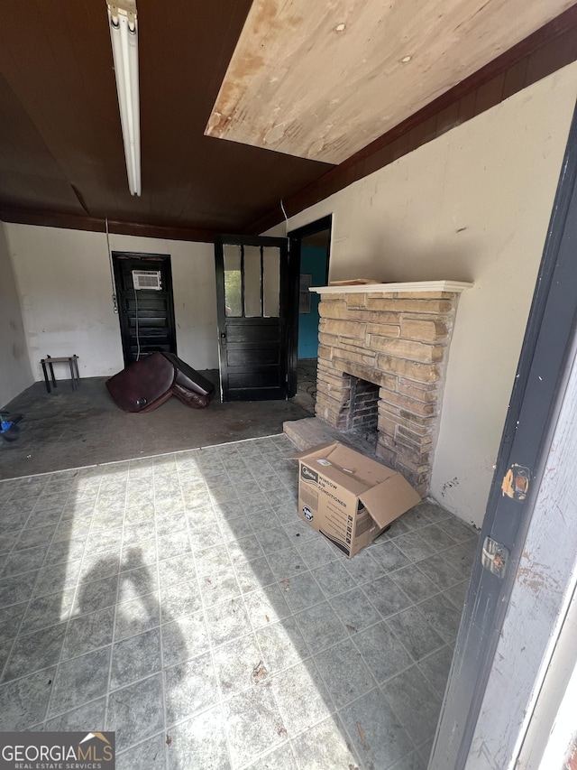 unfurnished living room with wooden ceiling and a stone fireplace