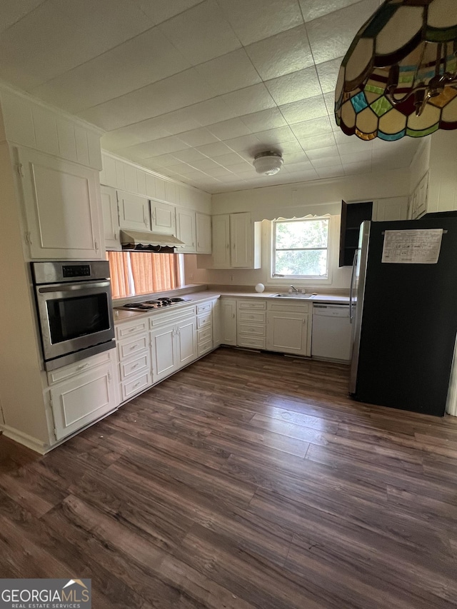 kitchen featuring appliances with stainless steel finishes, dark wood finished floors, light countertops, a sink, and white cabinets