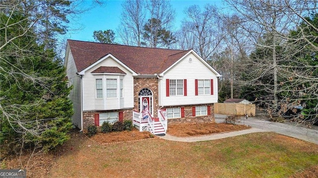 bi-level home with brick siding and a front yard