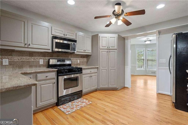 kitchen with light wood finished floors, recessed lighting, backsplash, a ceiling fan, and appliances with stainless steel finishes