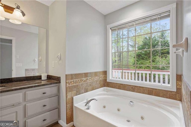 full bathroom featuring a jetted tub, vanity, and plenty of natural light