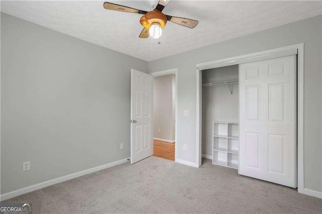 unfurnished bedroom with a closet, carpet flooring, baseboards, and a ceiling fan