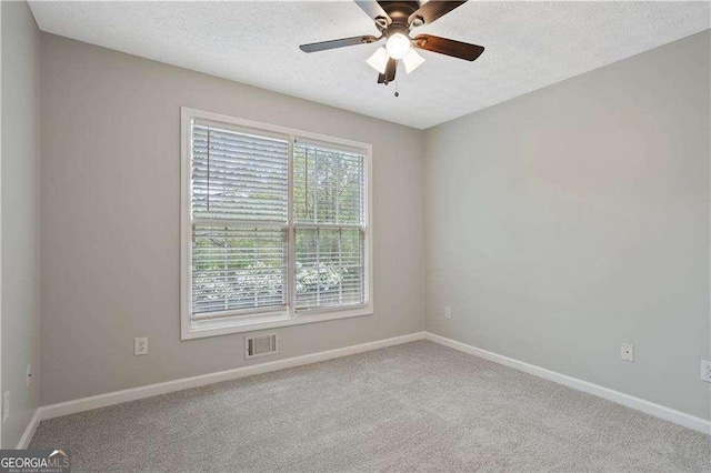 empty room featuring a textured ceiling, visible vents, baseboards, ceiling fan, and carpet floors