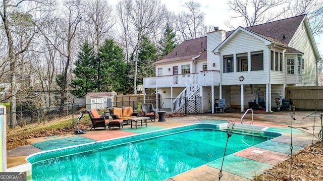 back of property with a fenced in pool, a fenced backyard, a wooden deck, a patio area, and stairs