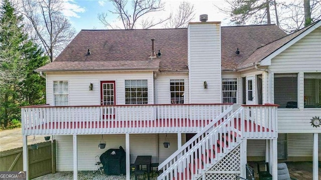 back of house featuring a chimney, roof with shingles, a deck, and stairway