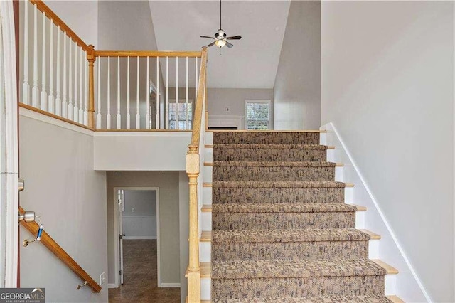 stairway featuring baseboards, high vaulted ceiling, and ceiling fan